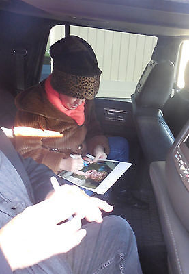 Bette Midler signing aurographs in the backseat of an automobile.