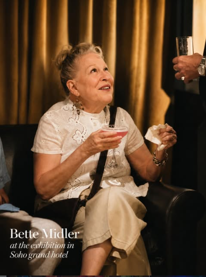 Older woman in a white lace blouse sits with a pink cocktail, as a man offers a drink nearby in a dim, gold-curtained room.