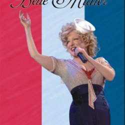 2026-05-25_00-24-20 - bootleg betty Bette Midler performing on stage with a microphone, wearing a sparkly blouse and dark pants, against a red-white-blue vertical striped background with cursive text at the top.