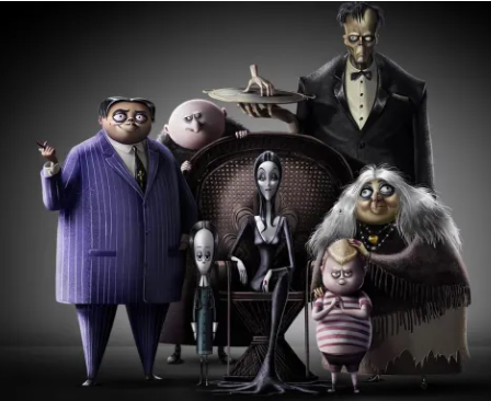 The Addams Family posed in a moody studio: Gomez in a purple pinstripe suit, Morticia center, Wednesday, Pugsley, Uncle Fester, Grandmama, and tall Lurch behind them.