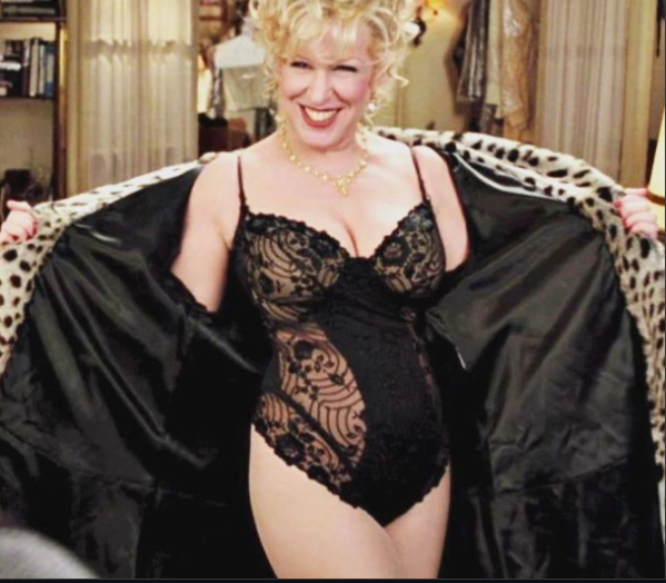 Smiling woman in black lace lingerie with an open leopard?print robe, posing indoors.