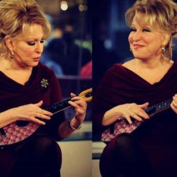Older woman in a burgundy dress playing a small string instrument (ukulele) on a TV studio set; two mirrored poses show different facial expressions.