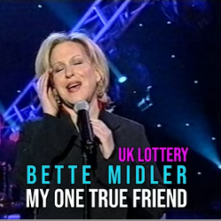 Bette Midler performing 'My One True Friend' on a stage with blue lights for a UK Lottery promo.