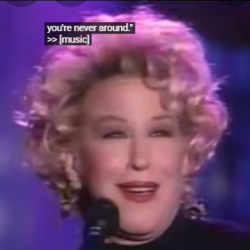 Female singer with curly blonde hair holding a microphone on stage; on-screen caption reads 'you're never around! >> [music]'. Social handle @boodles_bonbon visible.