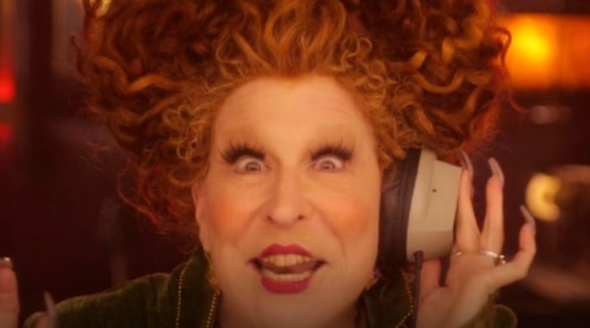 Woman with bright red curly hair wearing large over-ear headphones, eyes wide in surprise.