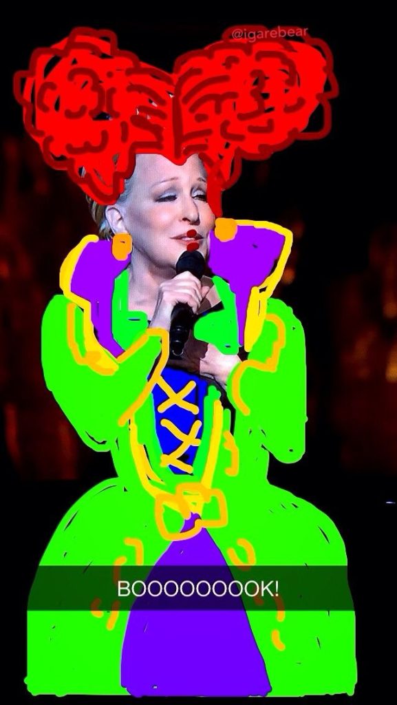 Performer on stage wearing a neon green and purple outfit, holding a microphone, with red drawn hair and the caption 'BOOOOK!'