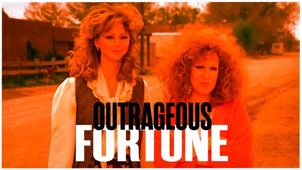 Poster-style photo of two women outdoors with an orange overlay and the bold title 'OUTRAGEOUS FORTUNE' covering the lower half of the image.