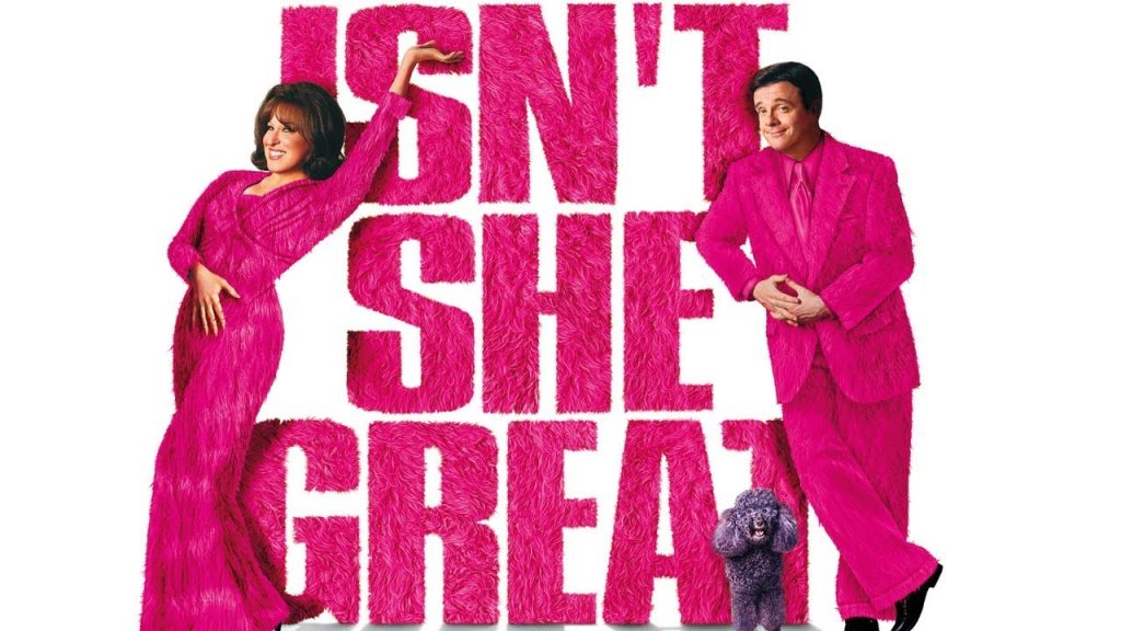 Promotional poster for a comedy: a woman and a man in bright pink fur outfits pose beside oversized pink text with a small gray poodle at their feet.