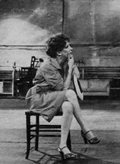 19be36b7b3ee3841f792ef726413f821 - bootleg betty Black-and-white photo of a woman in a dress sitting on a small chair, elbows on knees, chin resting on her hands in an industrial-looking space