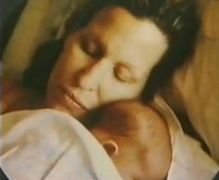 392273_229833747090270_221327031274275_558317_578336823_n-450x371 - bootleg betty Mother cradling a sleeping newborn close to her chest in bed.