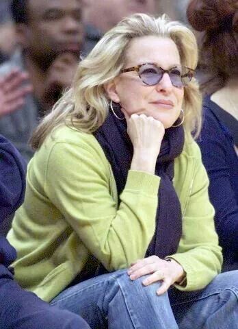 63813bd3a2f1c4d95c98c57c9716b982 - bootleg betty Woman in a lime-green jacket and black scarf sits pensively with her chin resting on her hand at an outdoor event.