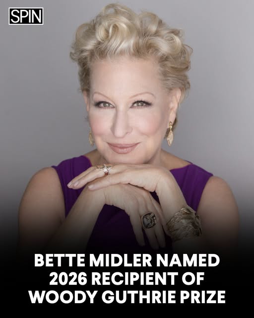 Portrait of Bette Midler smiling, wearing a purple dress, with hands folded under her chin; SPIN logo top-left and a headline stating she is the 2026 Woody Guthrie Prize recipient.