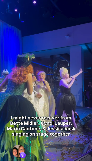 Stage performance with three performers in glittery costumes singing on a brightly lit stage, blue lights and confetti on the floor; on-screen caption mentions singing on stage together.