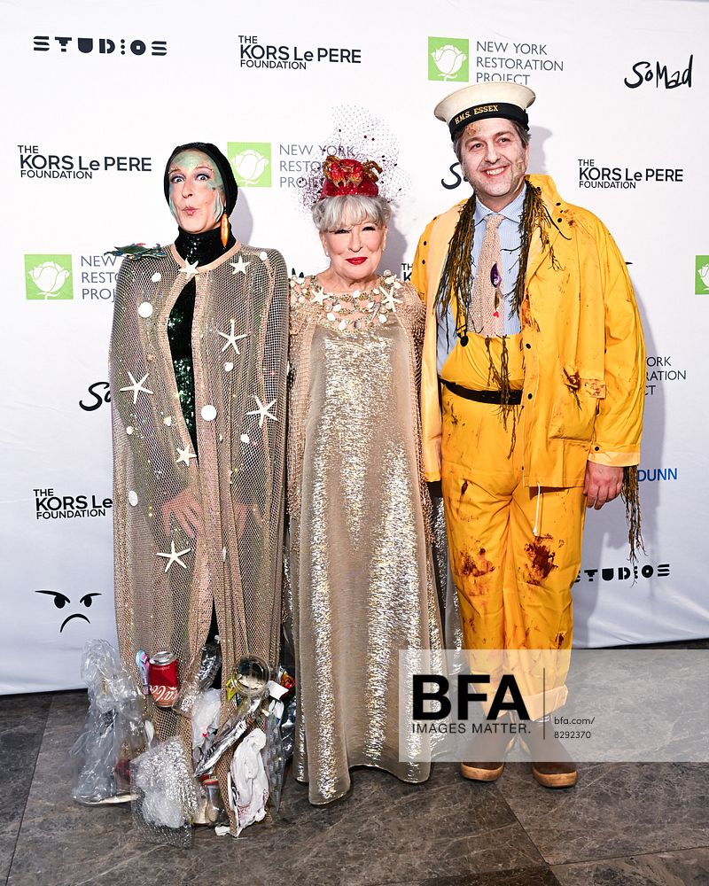 Three costumed adults pose on a red-carpet backdrop with charity logos; left in a starry cape, center in a sparkly gown with a crown, right in a yellow rain-slicker.